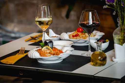  a table with white and black risotto and glass of white and red wine