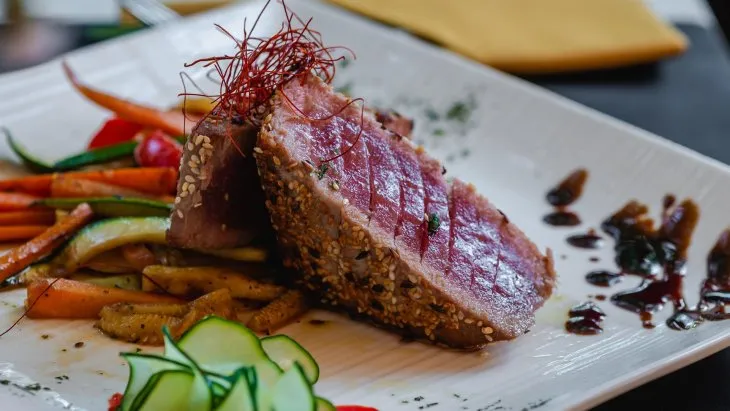  tuna steak in sesame and flex seeds with julienne vegetables on a plate