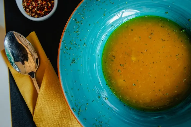  a plate with fish soup with cutlery on the side of the plate