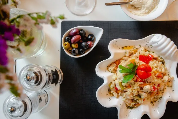  a table set with olives and a plate of of zucchini risotto