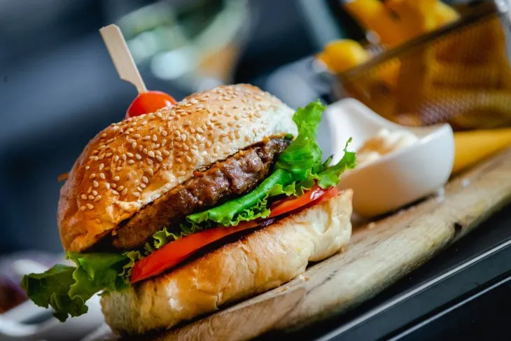  a beef burger served on a wooden plate