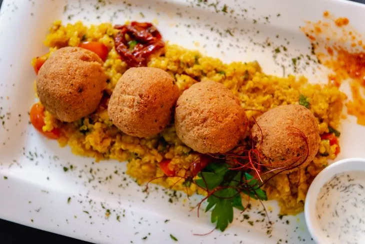  a white plate with four falafel balls on a bed of quinoa 